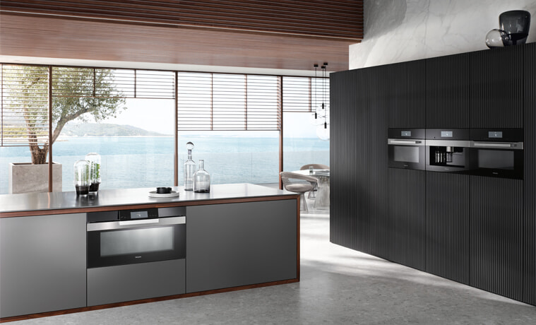 A sleek dark kitchen with Miele kitchen appliances.