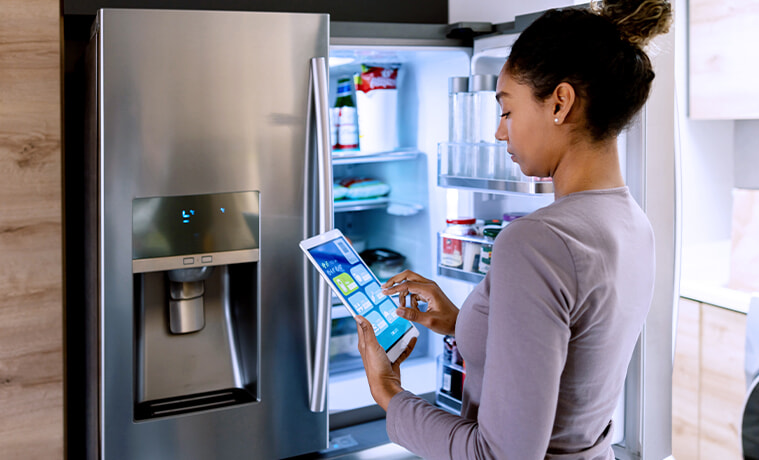 Woman controlling her smart fridge using an app on a tablet.