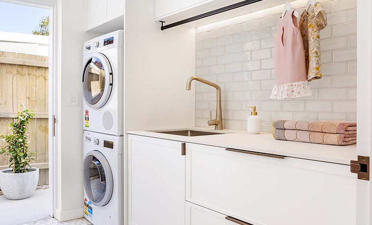 Coastal beauty laundry with stacked white Bosch appliances. 
