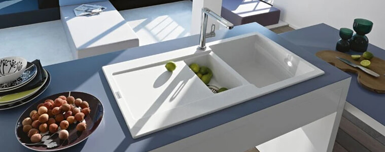 A white fragranite sink on a blue benchtop.