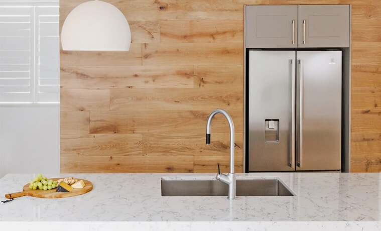A silver kitchen tap matches the silver kitchen appliances in a timber-filled kitchen.
