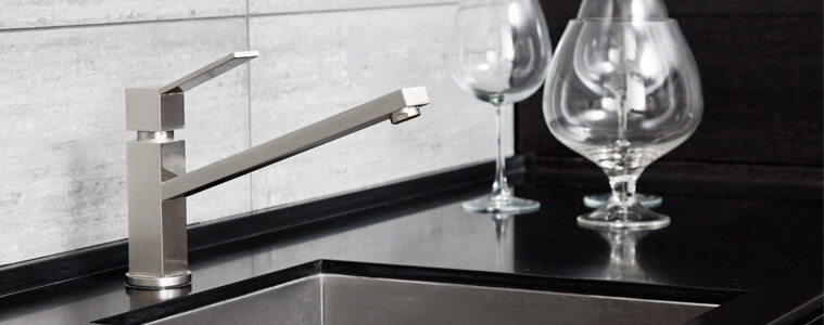 A brushed silver single lever mixer tap in a grey and black kitchen.