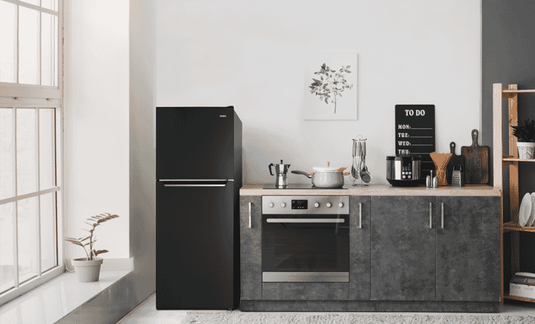 A black CHiQ fridge sits in a grey kitchen with white walls.