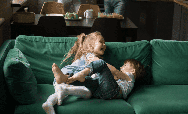 Happy children playing on their couch. 