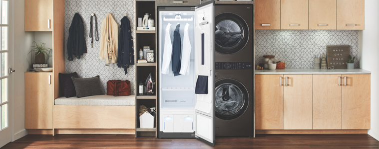 A black drying cabinet next to a matching washer and dryer in a warm-toned timber laundry.