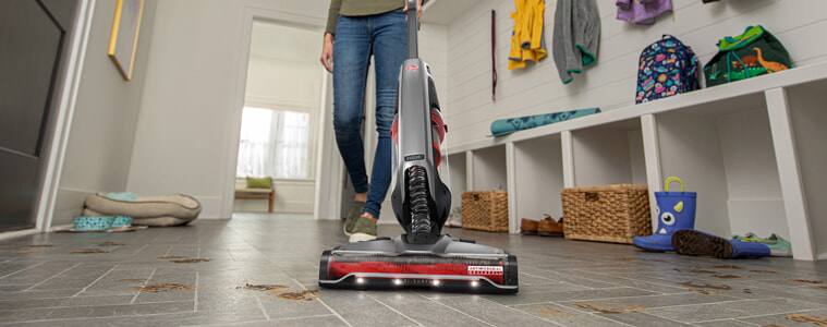 A person vacuums their front entry way.