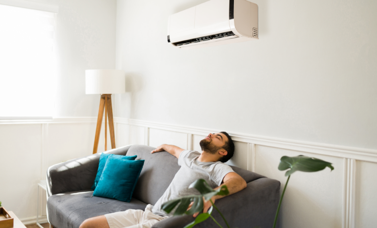 man relaxes on couch underneath an aircon