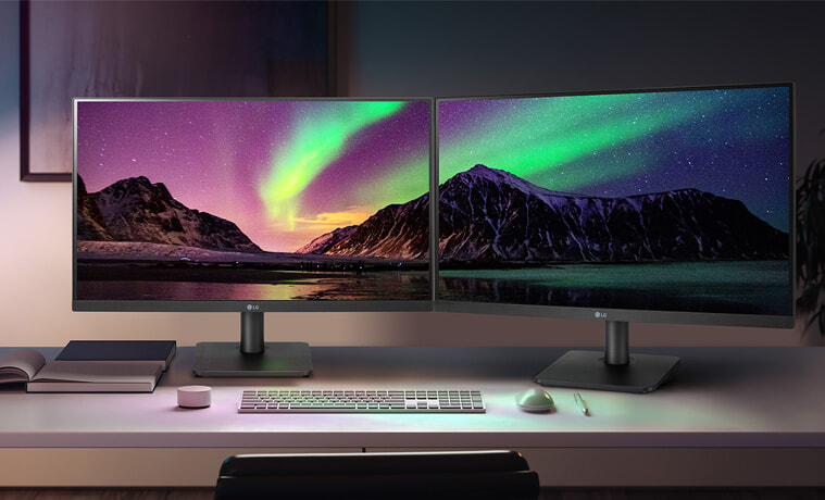 Two LG monitors stand side-by-side in a home study.