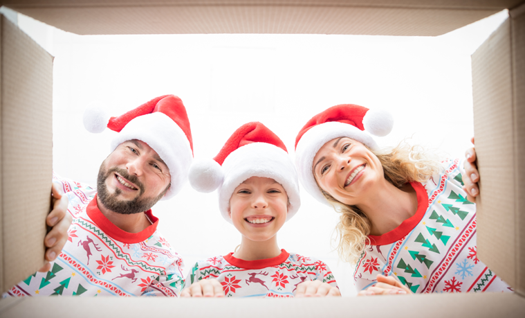 A happy family in matching Christmas pyjamas looking into a gift box.