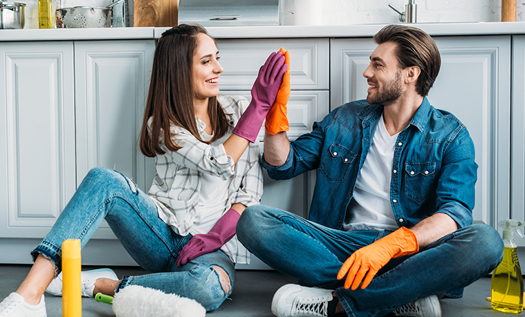 Happy couple smiling to each other while cleaning