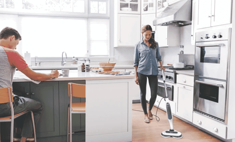 Someone using a steam mop in their kitchen