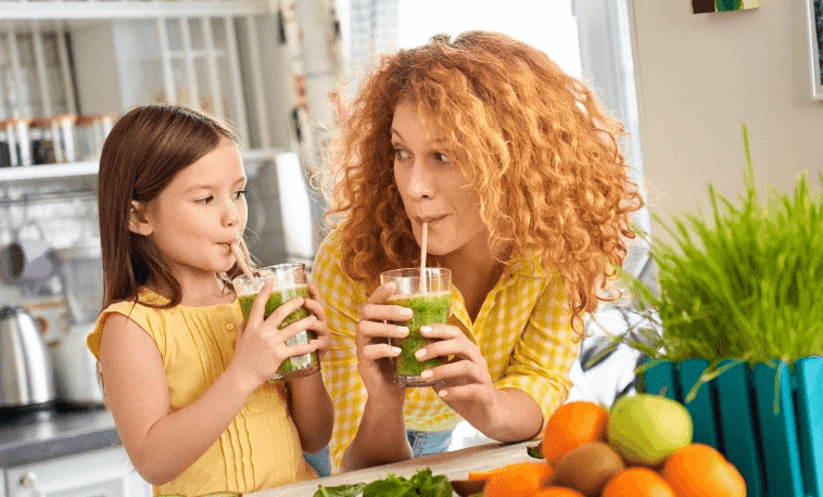 Mother and daughter in kitchen drinking smoothies