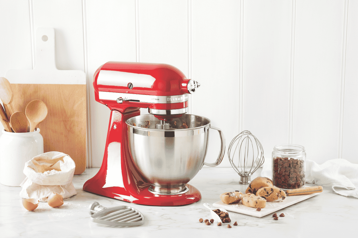 A red KitchenAid Stand Mixer sits on a kitchen bench filled with yellow smoothie