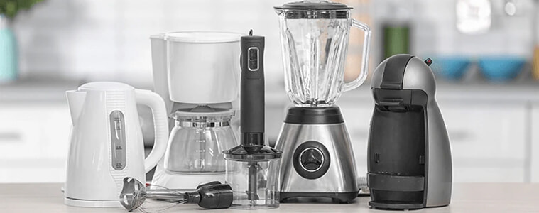 From left to right: A white kettle, a white coffee pot, a black hand blender, a chrome blender, and a chrome small kitchen appliance.