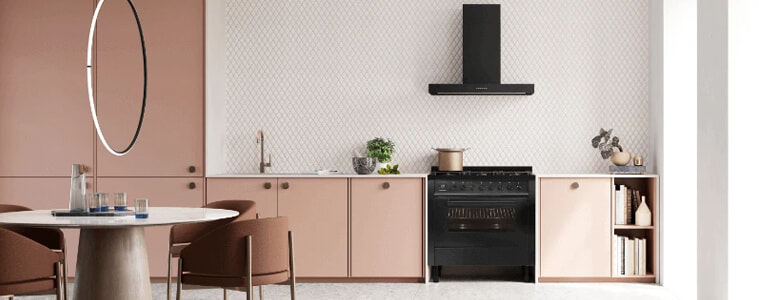 A stylish pink kitchen with a black freestanding oven.