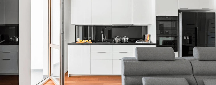 A small white kitchen with a large black smart fridge.