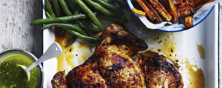 Portuguese roast chicken with sweet potato fries on a rectangular white plate.