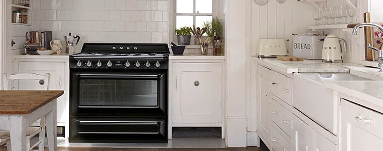 A black Smeg Victoria freestanding oven in a white country-style kitchen.