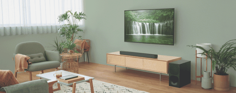 A soundbar sits on a television console and projects audio around the living room.