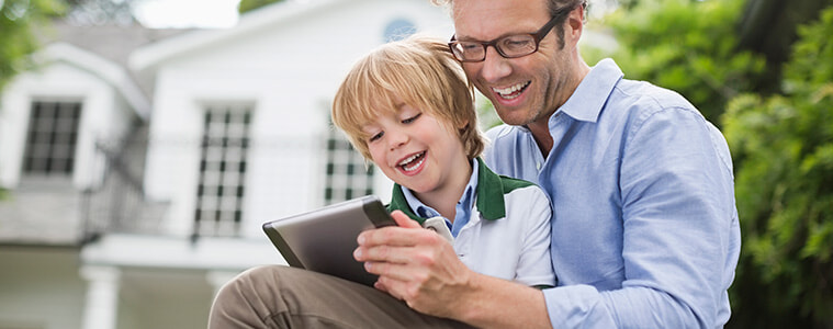 Father and young son using a digital tablet outdoors.