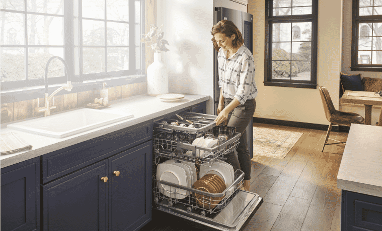 Woman loading her LG QuadWash dishwasher in kitchen. 