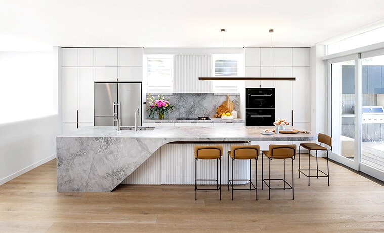 Contemporary open plan kitchen with white cabinetry and a central island bench topped with grey marble.