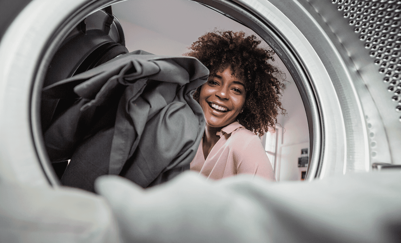 Smiling Woman loading clothes into her new clothes dryer