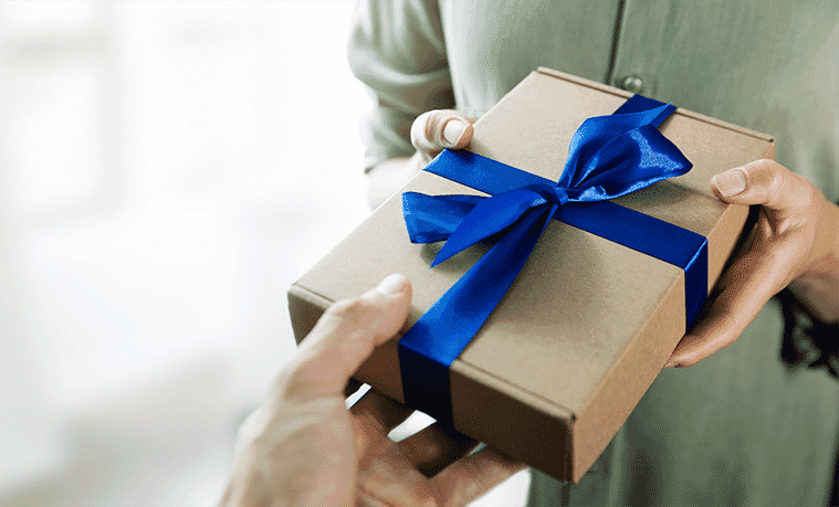 A wrapped gift with a blue bow being given to a friend