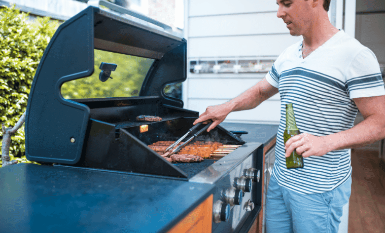 A man cooks sausages on the built-in barbecue on his outdoor deck