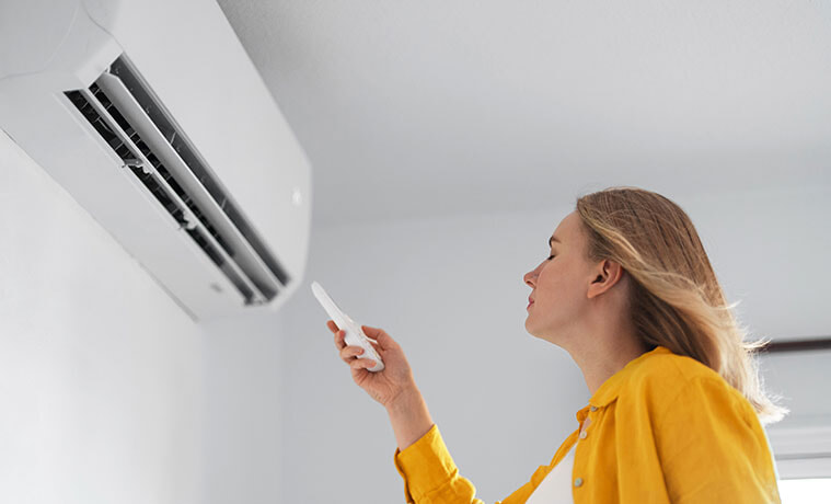 A woman enjoys a blast of cool air from her wall-mounted air conditioner