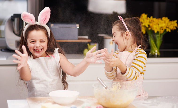 Two playful sisters having fun baking Easter treats in the kitchen