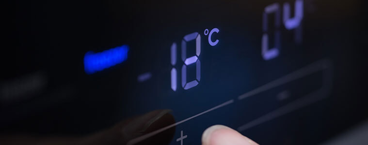 Close-up of a man setting the  temperature on a digital control panel in a fridge