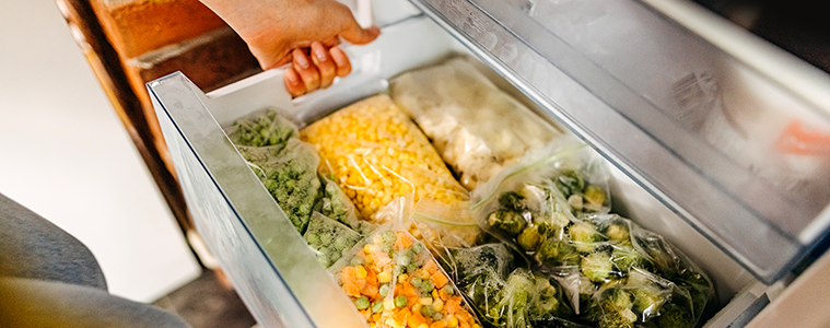 A woman opens the freezer drawer of her fridge