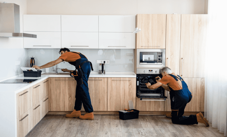 Two workers renovate a kitchen and install new appliances