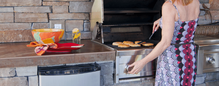 Woman cooks on her built-in BBQ in her outdoor kitchen