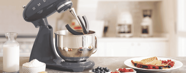 Image of the Smeg 50's Style Stand Mixer on a kitchen bench with a plate of crepes and ingredients.