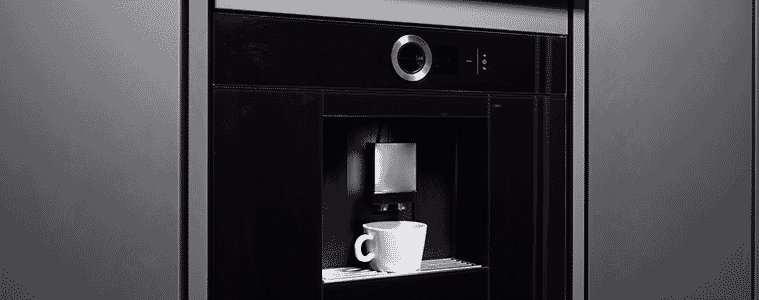 Coffee pours into a white cup sitting in a built-in coffee machine in a butler’s pantry