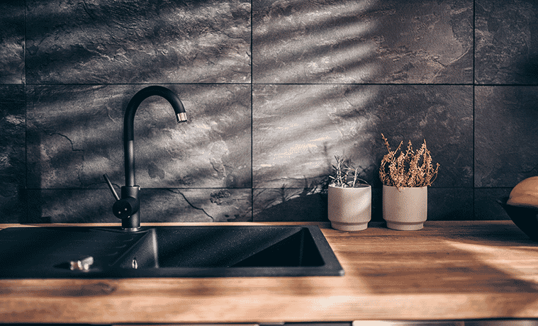 Modern black gooseneck tap and matching matte black inset sink in a kitchen filled with warm afternoon light