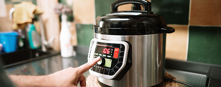 Close-up of hand touching a button on a slow cooker