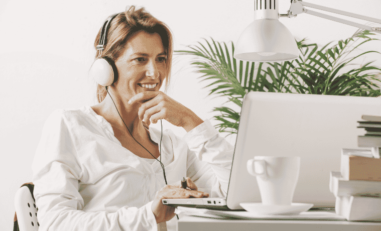 Woman smiles while sitting in front of her laptop in a home office