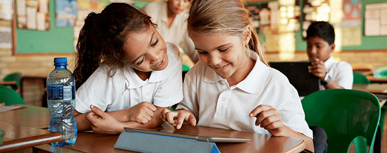 Two primary school aged girls share a tablet in the classroom