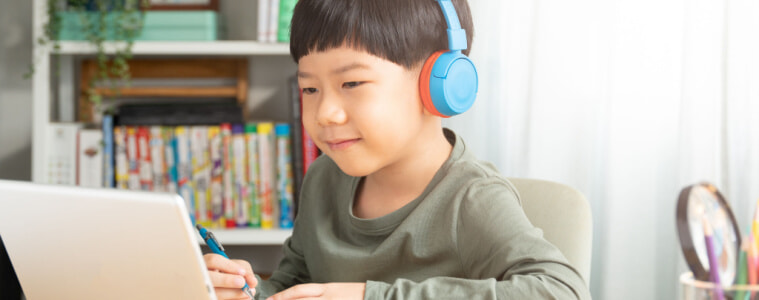 A young boy uses a tablet while wearing headphones