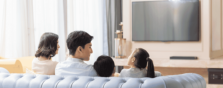 Rear view of a family watching TV on a blue couch in the living room