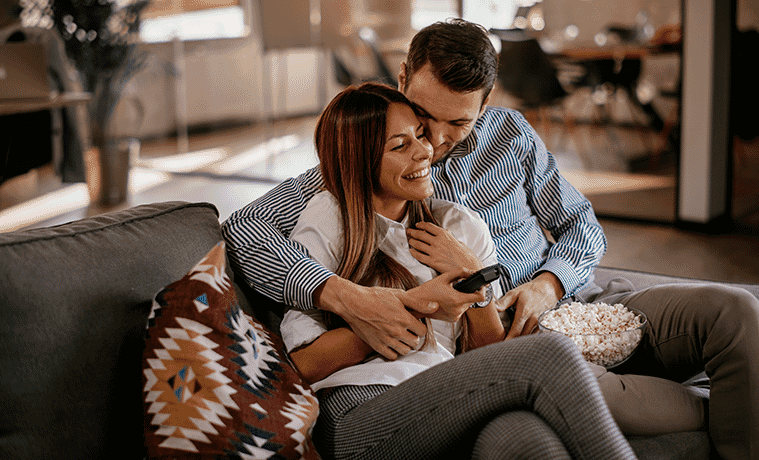 Couple at home, cuddling on the couch, watching TV