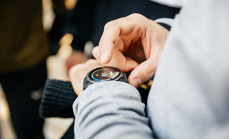 Close-up of a man in a grey tracksuit checking stats on the screen of his smartwatch