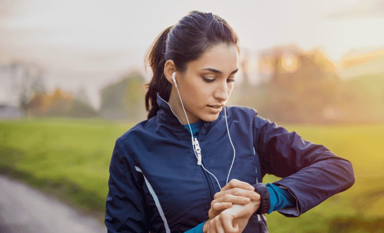 Athletic woman using a smartwatch during her fitness workout on a running path.  
