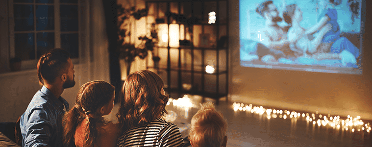 a family sitting together watching a movie on their projector 