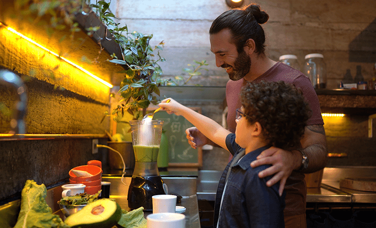Father and son prepare a smoothie at home using a blender