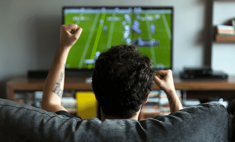 Man at home watching football on a big screen TV