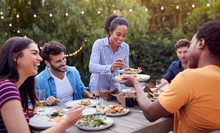 friends and family sitting outside together enjoying a home cooked meal 